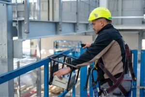 mateco platformon áll a kezelő, munkavédelmi sisakban és hevederben